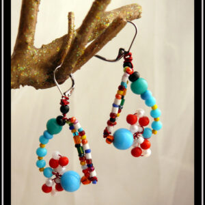 Boucles d'oreilles montées sur dormeuses en acier.Perles multicolores en verre et rocailles multicolores. Dominante bleue turquoise et rouge