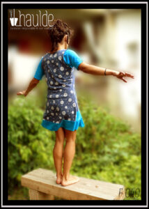 Robe sans manche très échancrée et top manches mi longues en jersey bleu ciel. Robe en jersey bleu jean imprimé pissenlits en graines blanc et volant de velours bleu ciel Vue portée par une femme debout de dos