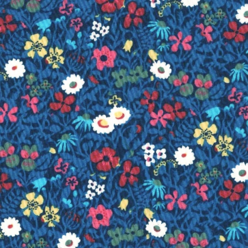 détail du tissu liberty fond bleu foncé, feuillage bleu électrique, petites fleurs de diverses formes roses jaune rouge blanche et bleu pale