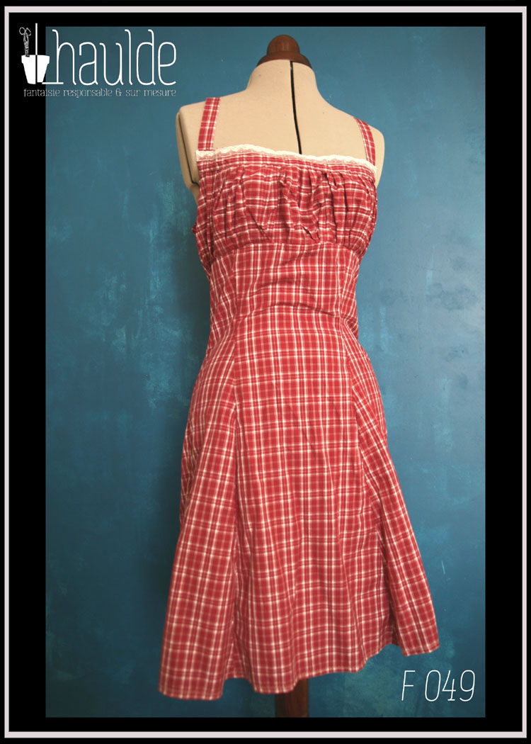 Robe d'été à bretelles croisées dans le dos en batiste légère en écossais rouge bordeaux et blanc avec un ruban de dentelle blanche au niveau du décolleté. Vu en pied de face