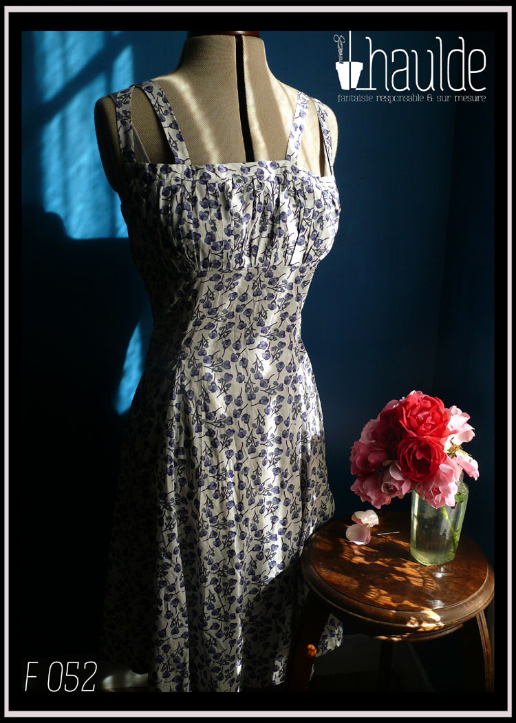 Robe d'été à double bretelles en batiste imprimée pensées violettes et mauves, buste plissé, taille ajustée, jupe ample. Vue de face sur un mannequin couture