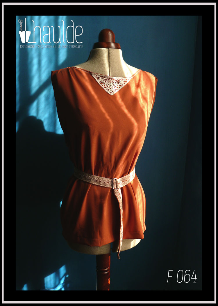 Tunique en crêpe terracotta garnie au niveau de l'encolure d'un triangle de dentelle vintage sur le devant. Ceinture assortie en crêpe recouverte de dentelle rose très pâle Vue de face sur un mannequin couture avec la ceinture au soleil