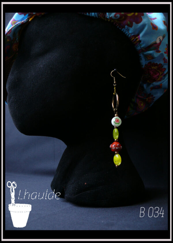 Boucles d'oreilles asymétriques perles en verre ovales et rondes avec inclusion ou peintes, multicolores, anneaux dorés le tout monté sur crochets acier doré Vue sur un mannequin tête