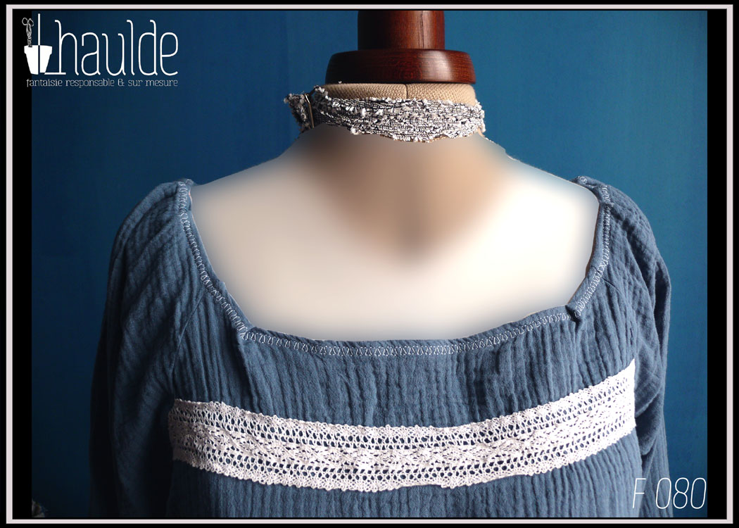 Mannequin couture portant le haut décrit dans la fiche, en double gaze de coton bleu jean avec une bande de dentelle blanche au-dessus du buste. Grande encolure et manches raglan longues Vue de détail de l'encolure et du buste