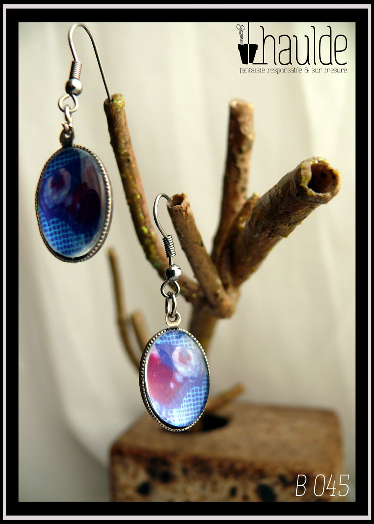Paire de boucles d'oreilles montées sur crochet acier avec une photo d'aile de paon du jour vue en gros plan sou un cabochon loupe en verre. Pendentif ovale