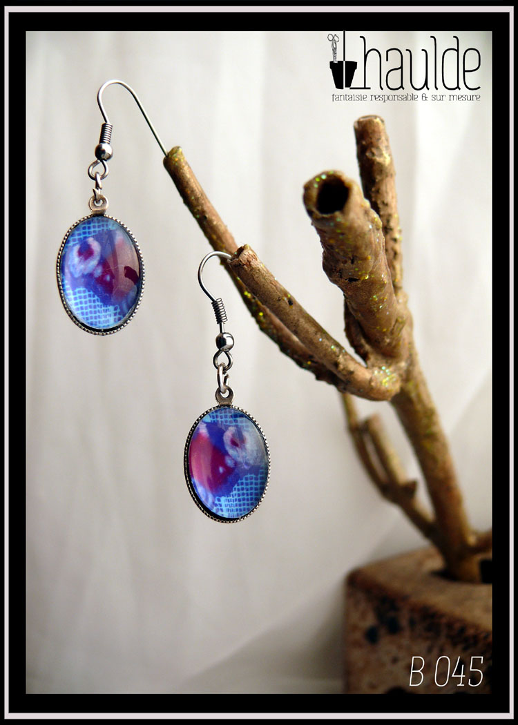 Paire de boucles d'oreilles montées sur crochet acier avec une photo d'aile de paon du jour vue en gros plan sou un cabochon loupe en verre. Pendentif ovale