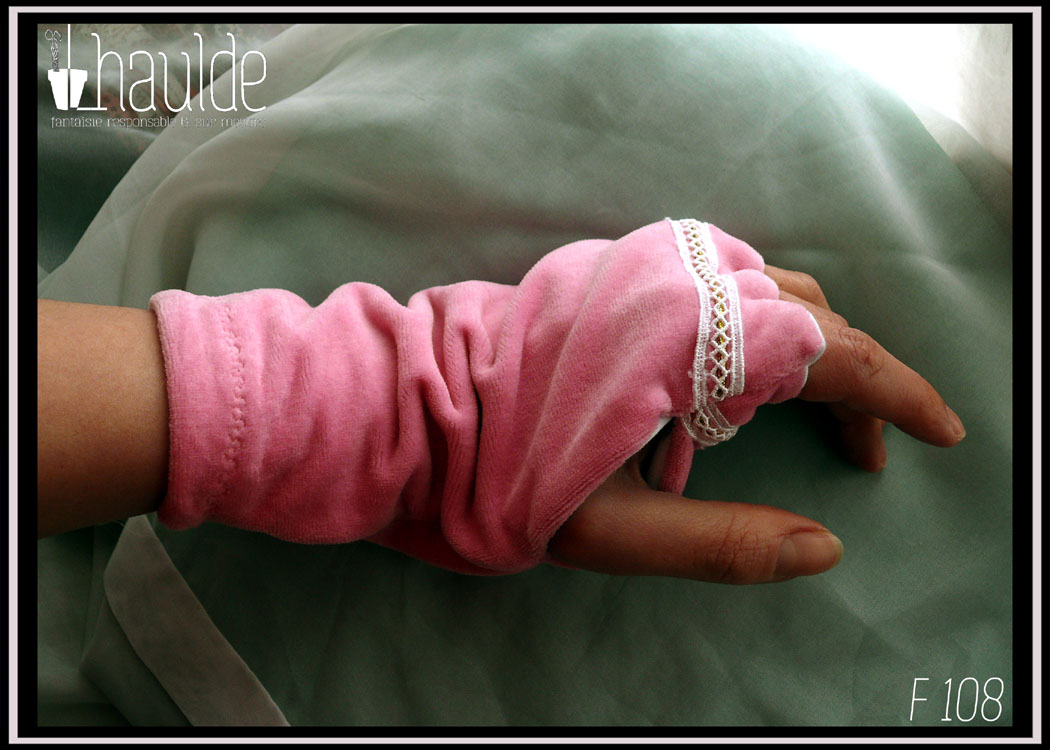 paire de mitaines en velours rose avec un galon de dentelle et une tresse tubulaire en décoration, intérieur en jersey blanc, doigt formés, poignet serré vue de profil