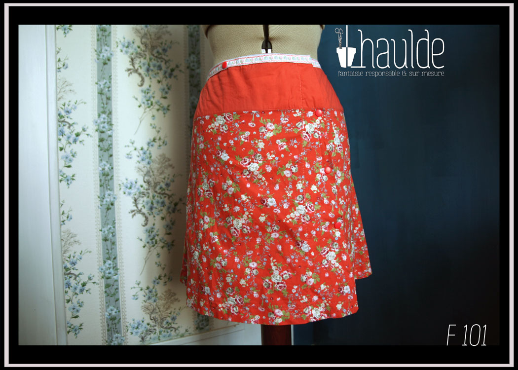 Jupe portefeuille courte en toile corail imprimé fleurs, haut corail avec un galon brodé blanc à fleurs. Vue de face sur un mannequin couture