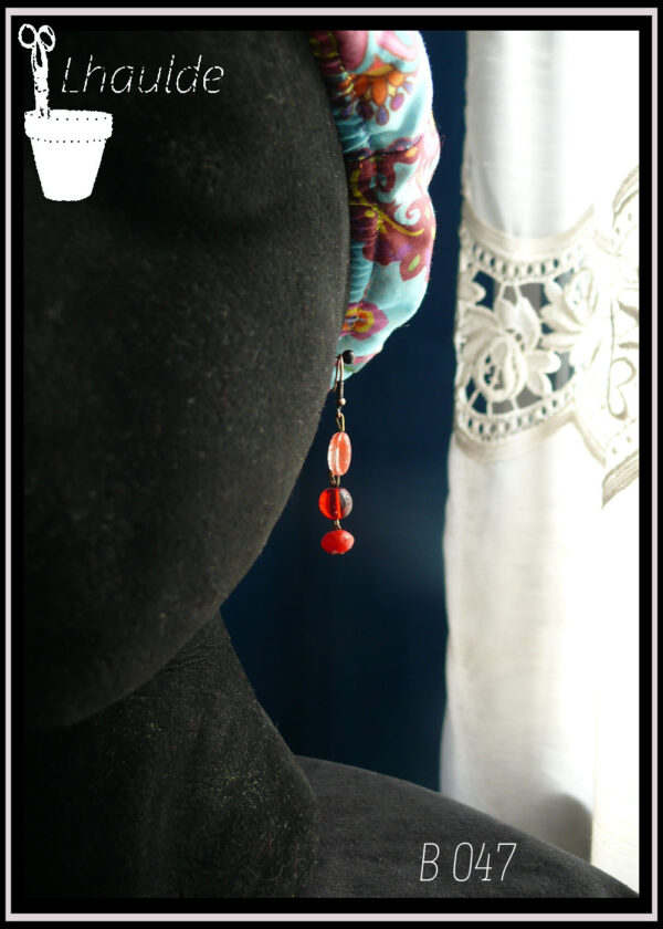 Boucles montées sur crochet, perles alignées à la verticale, ovale plate striée de rouge, ronde rouge transparente, galet rouge transparente Vue sur une tête de mannequin