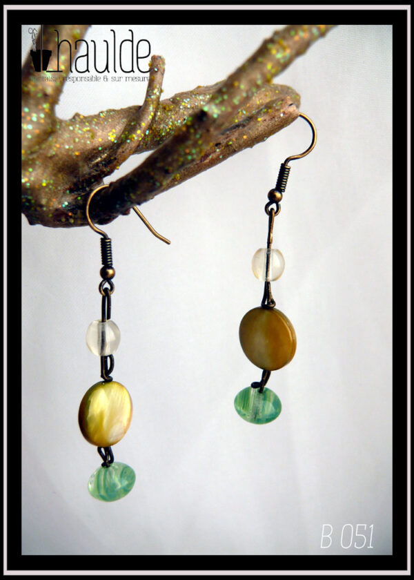 Boucles d'oreilles montées sur crochets d'acier doré, perles alignées à la verticale sur une tige d'acier : petite ronde en verre transparent, perle disque plat en nacre jaune, perle galet en verre vert transparent