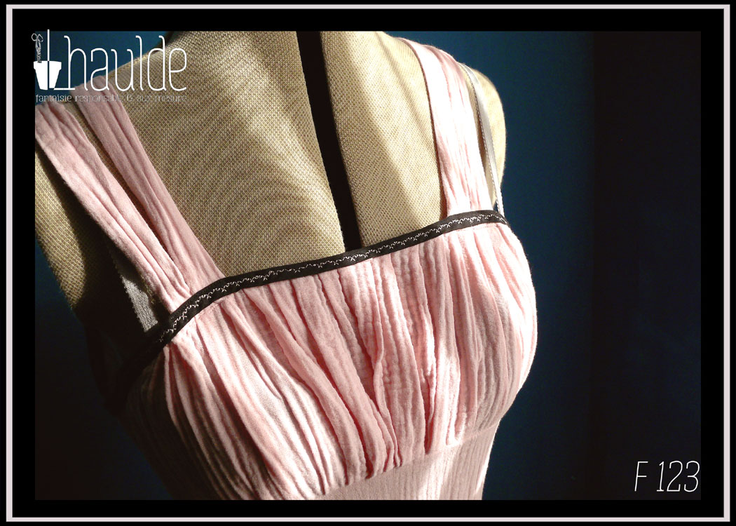 plan rapproché du buste Robe d'été à bretelles en double gaze rose pâle, galon de dentelle noire au bas de la robe, biais noir autour du haut du buste. buste plissé, taille ajustée, jupe évasée.