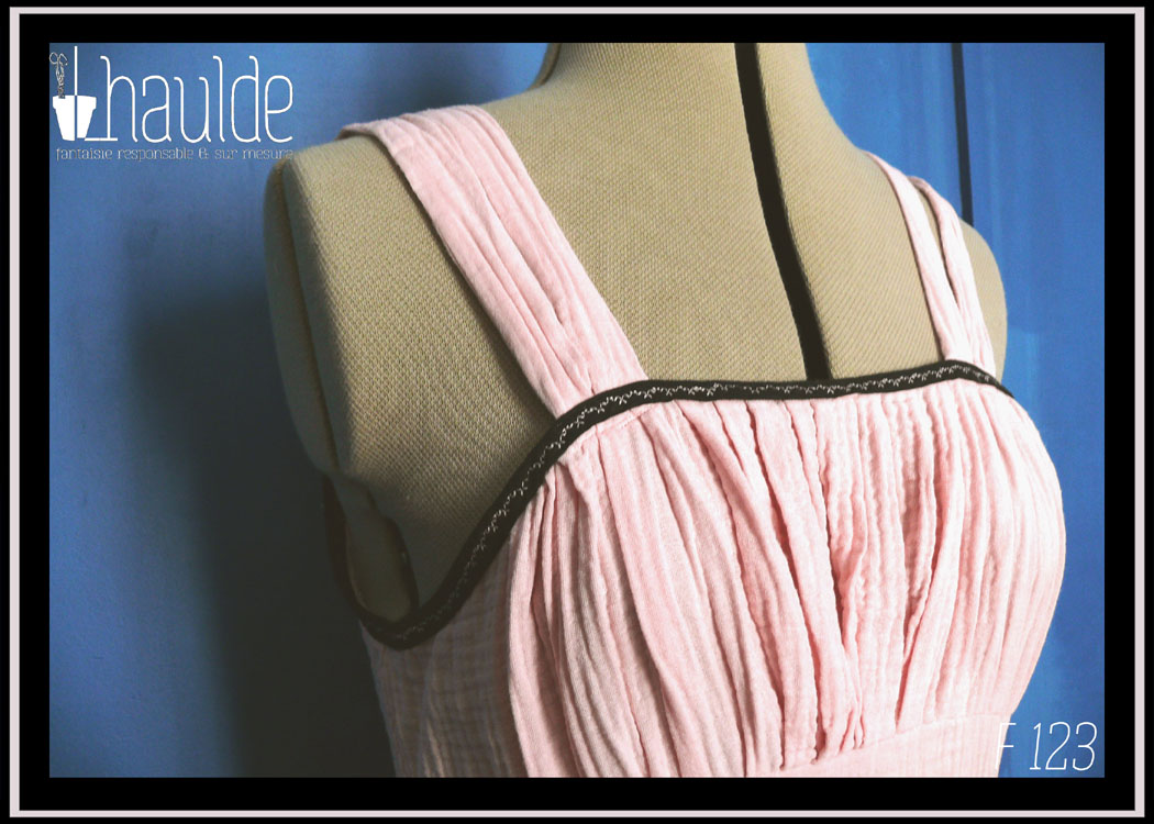 plan rapproché du buste sur mannequin de couture Robe d'été à bretelles en double gaze rose pâle, galon de dentelle noire au bas de la robe, biais noir autour du haut du buste. buste plissé, taille ajustée, jupe évasée.