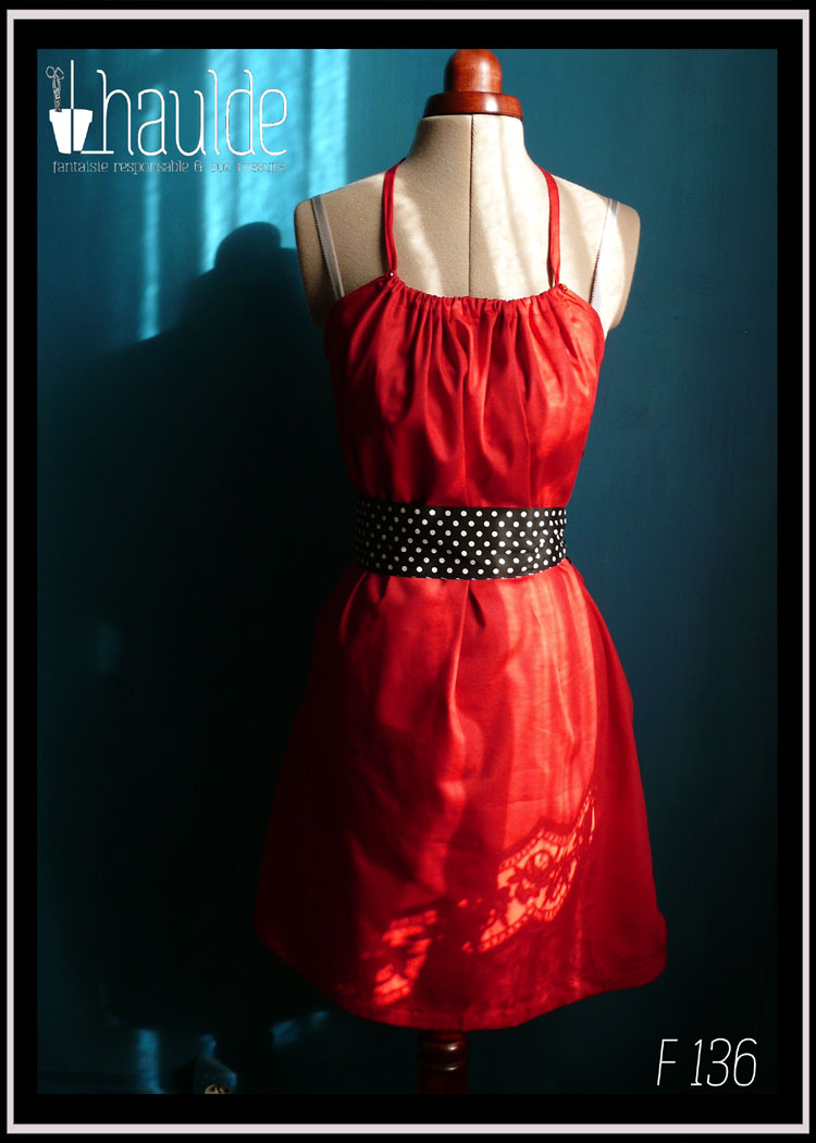 Robe courte dos nu en satin rouge certifié oeko tex, ceinture et poches plaquées en tissu noir à pois blancs vue de face en pied au soleil