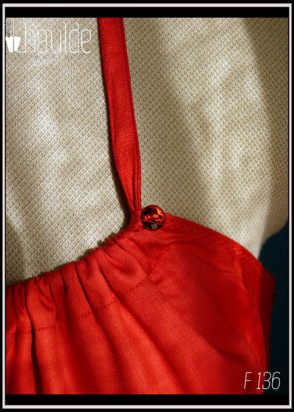 Robe courte dos nu en satin rouge certifié oeko tex, ceinture et poches plaquées en tissu noir à pois blancs Vue de détail des boutons décoratifs en haut du buste