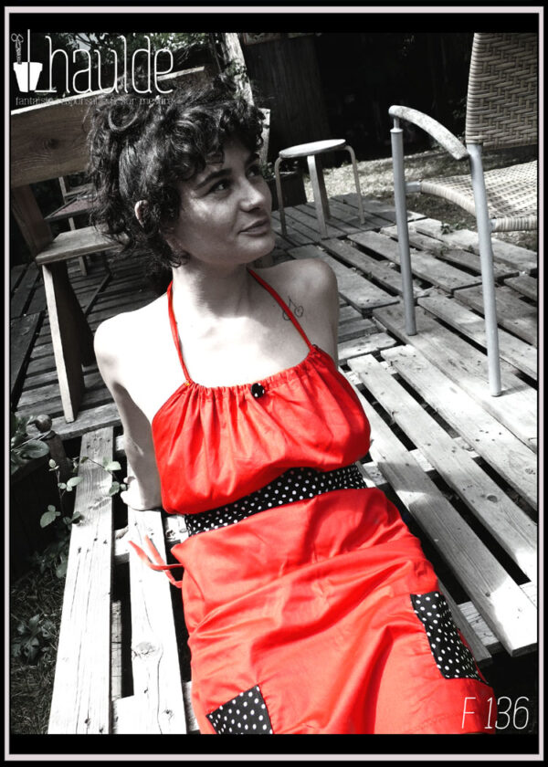 Robe courte dos nu en satin rouge certifié oeko tex, ceinture et poches plaquées en tissu noir à pois blancs Vue portée de face assise