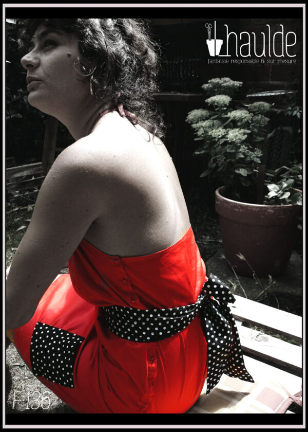 Robe courte dos nu en satin rouge certifié oeko tex, ceinture et poches plaquées en tissu noir à pois blancs vue portée de trois quarts dos