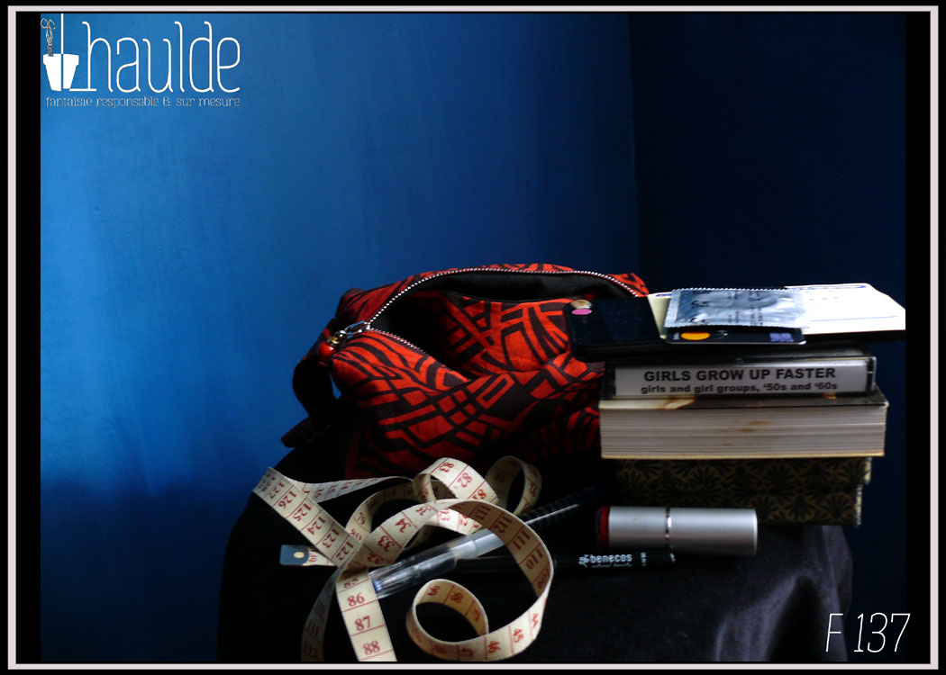 Mini sac en coton rouge imprimé noir (motifs graphiques type zèbre) Vue du sac + le contenu vidé sur la vidéo (un mini livre, une cassette audio, du rouge à lèvre, un smartphone, un mètre de couture...