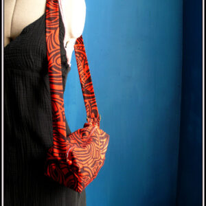 Mini sac en coton rouge imprimé noir (motifs graphiques type zèbre) Vue porté sur un mannequin couture en bandoulière du même côté (chute droite de l'épaule à la hanche)