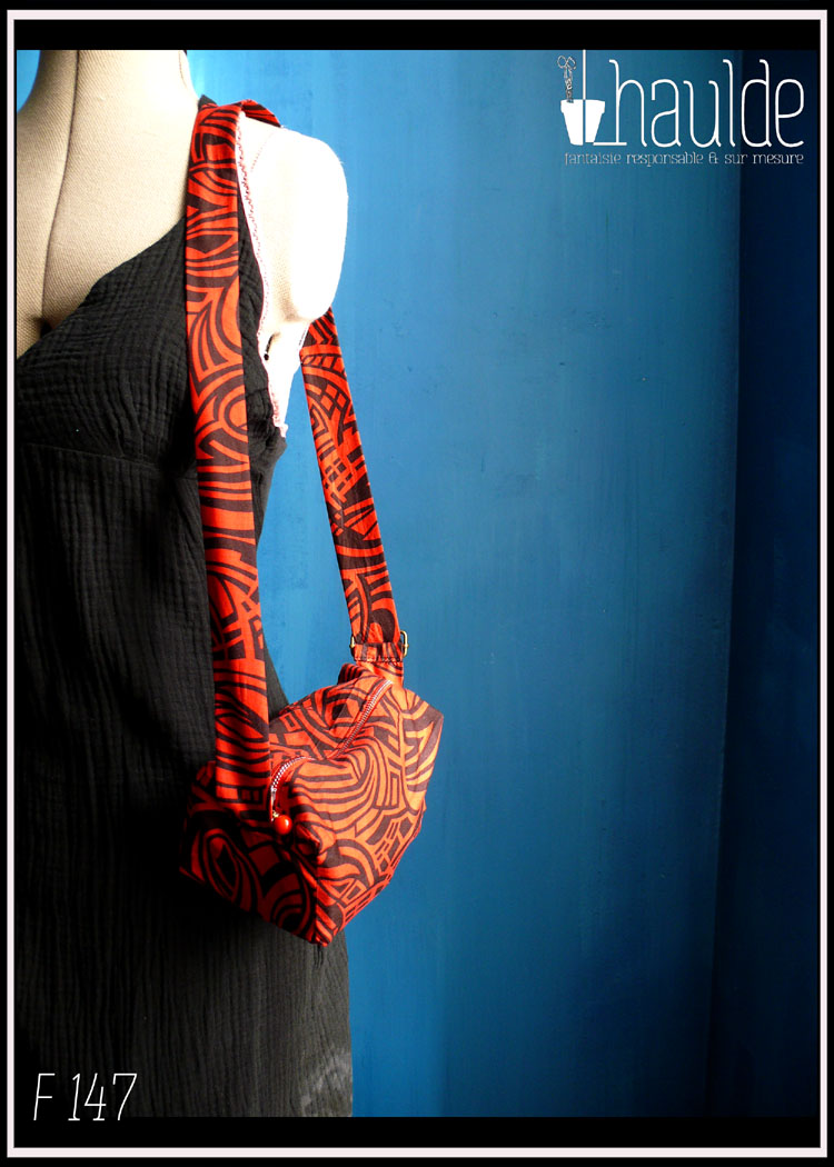 Mini sac en coton rouge imprimé noir (motifs graphiques type zèbre) Vue porté sur un mannequin couture en bandoulière du même côté (chute droite de l'épaule à la hanche)