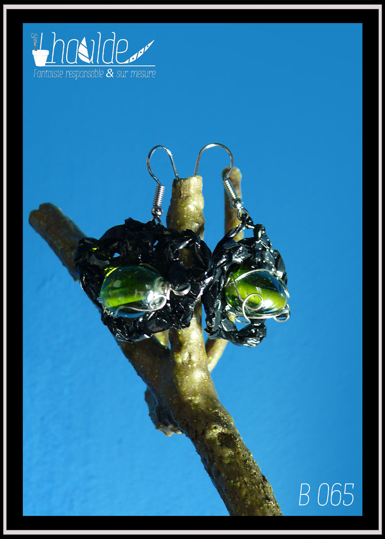 paire de boucles d'oreilles en VHS crochetée montée sur crochet d'acier. Vidéo crochetée de forme ovale avec en son centre une grosse perle en verre vert. Vue de la paire, de face