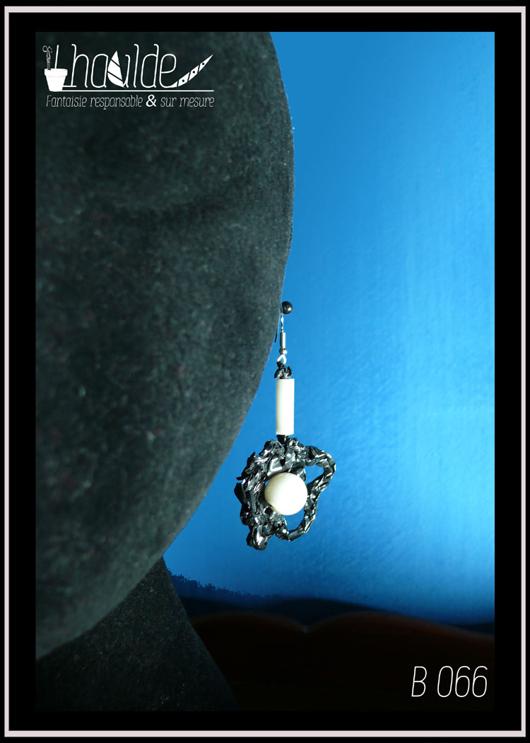 paire de boucles d'oreilles en bande video crochetée, avec au centre une perle en verre blanc vue sur un mannequin tête