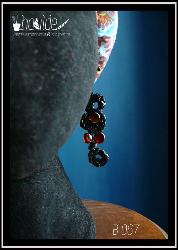Paire de boucles d'oreilles en bande video crochetée avec des perles en verre transparent oranges et rouges Vue sur un mannequin tete