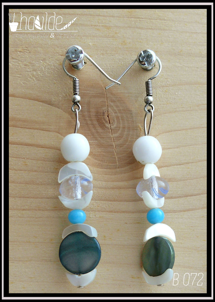 Paire de boucles d'oreilles montée sur crochets acier, perles alignées à la verticale, une ronde verre blanc opaque, une chips de nacre blanc en forme de demi-lune, une perle galet bleu pâle, une chips, une petite ronde bleu ciel, une chips, une perle disque plat en nacre bleue et une chips