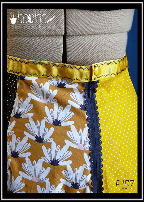 Jupe à pans amples, jaune à mini pois blancs, noir à mini pois blancs et imprimé fleurs blanches sur fond ocre, zip dentelle et ceinture jaune Vue de détail du zip