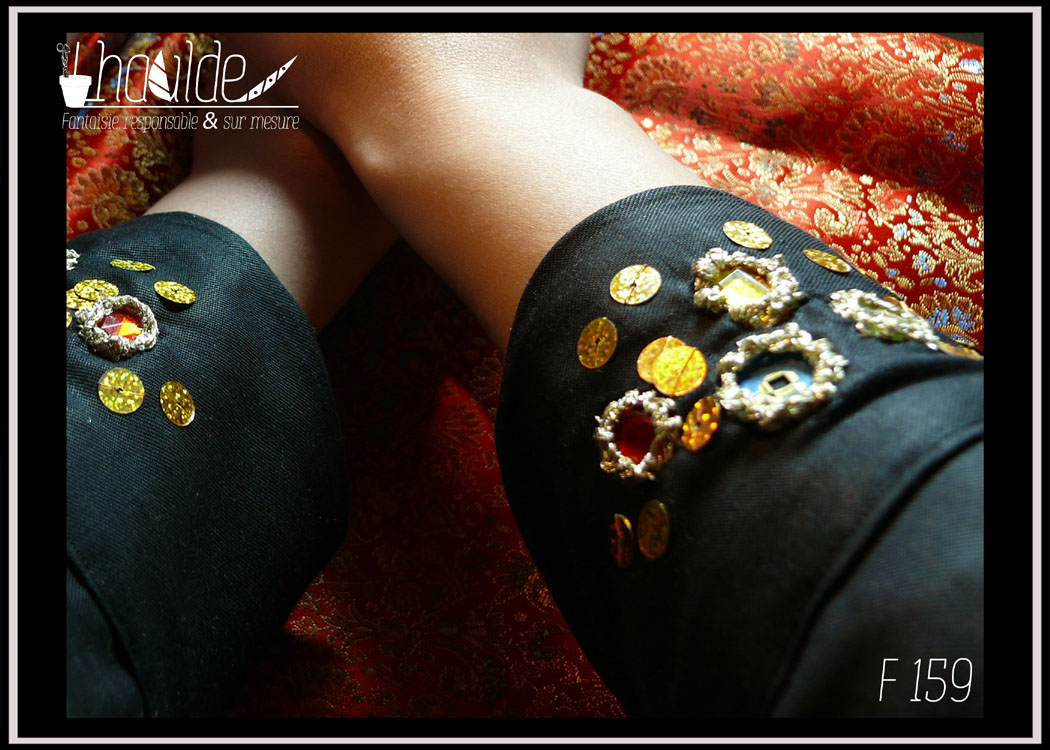 Tunique longue à manche longue. Centre, col, manches et dos en tencel noir. Manchettes brodées de perles et de miroirs. Côtés devant en soie rouge brocardée de motifs dorés Vue de détail des broderies des manchettes