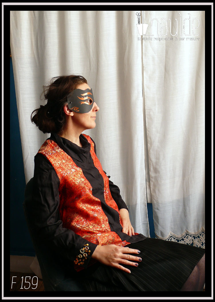 Tunique longue à manche longue. Centre, col, manches et dos en tencel noir. Manchettes brodées de perles et de miroirs. Côtés devant en soie rouge brocardée de motifs dorés Vue portée par une personne assise