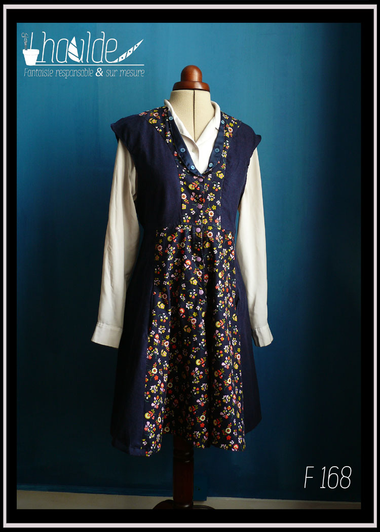 Robe en velours milleraies bleu marine, sans manche, avec le centre en velours milleraies bleu marine imprimé fleurs rouges jaunes et roses Vue de face avec un chemisier en dessous sur un mannequin couture