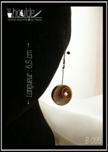 Paire de boucles d'oreilles, crochet acier. Bouton vintage en plastique beige suspendu à une tige en acier couleur bronze avec en son centre une demi-sphère en acier doré qui contient une perle cubique en verre blanc effet nacre. Longueur 6,5 cm