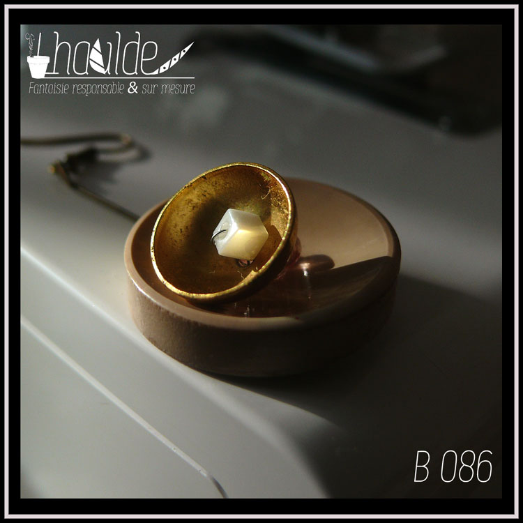 Paire de boucles d'oreilles, crochet acier. Bouton vintage en plastique beige suspendu à une tige en acier couleur bronze avec en son centre une demi-sphère en acier doré qui contient une perle cubique en verre blanc effet nacre. Longueur 6,5 cm