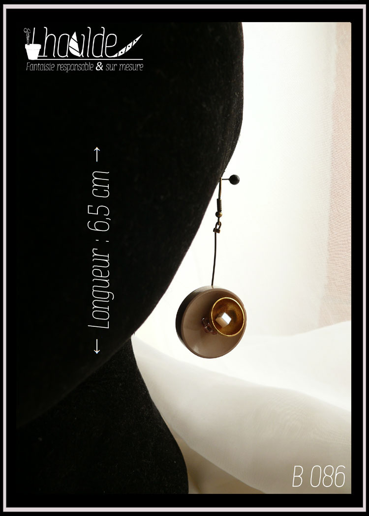 Paire de boucles d'oreilles, crochet acier. Bouton vintage en plastique beige suspendu à une tige en acier couleur bronze avec en son centre une demi-sphère en acier doré qui contient une perle cubique en verre blanc effet nacre. Longueur 6,5 cm