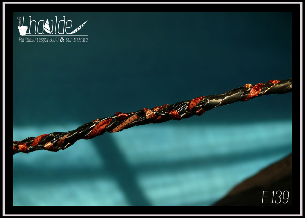 mini pochette en simili cuir noir doublé de coton imprimé motifs végétaux orange pâle sur fond vermillon. Devant couvert de VHS et fil de broderie crochetés Détail de la bandoulière tressée