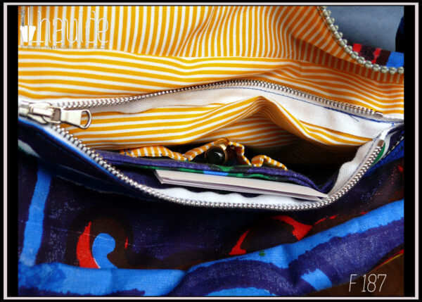 Sac en coton bleu foncé imprimé carrelage égyptien (grands motifs 40 x 40 cm) bleu rouge vert et jaune. Doublure intérieure jaune à rayures blanches Vue de détail de la grande poche intérieure zippée ouverte avec stylos dans les emplacements et carnets