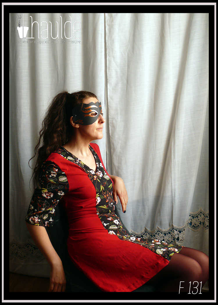 Robe mi-longue, manches mi-longues évasées en jersey, noir imprimé fleurs au centre sur toute la longueur devant et pour les manches. Jersey rouge cerise pour les côtés et le dos. vue portée, assise de profil