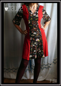 Robe mi-longue, manches mi-longues évasées en jersey, noir imprimé fleurs au centre sur toute la longueur devant et pour les manches. Jersey rouge cerise pour les côtés et le dos. vue de face en pied, portée