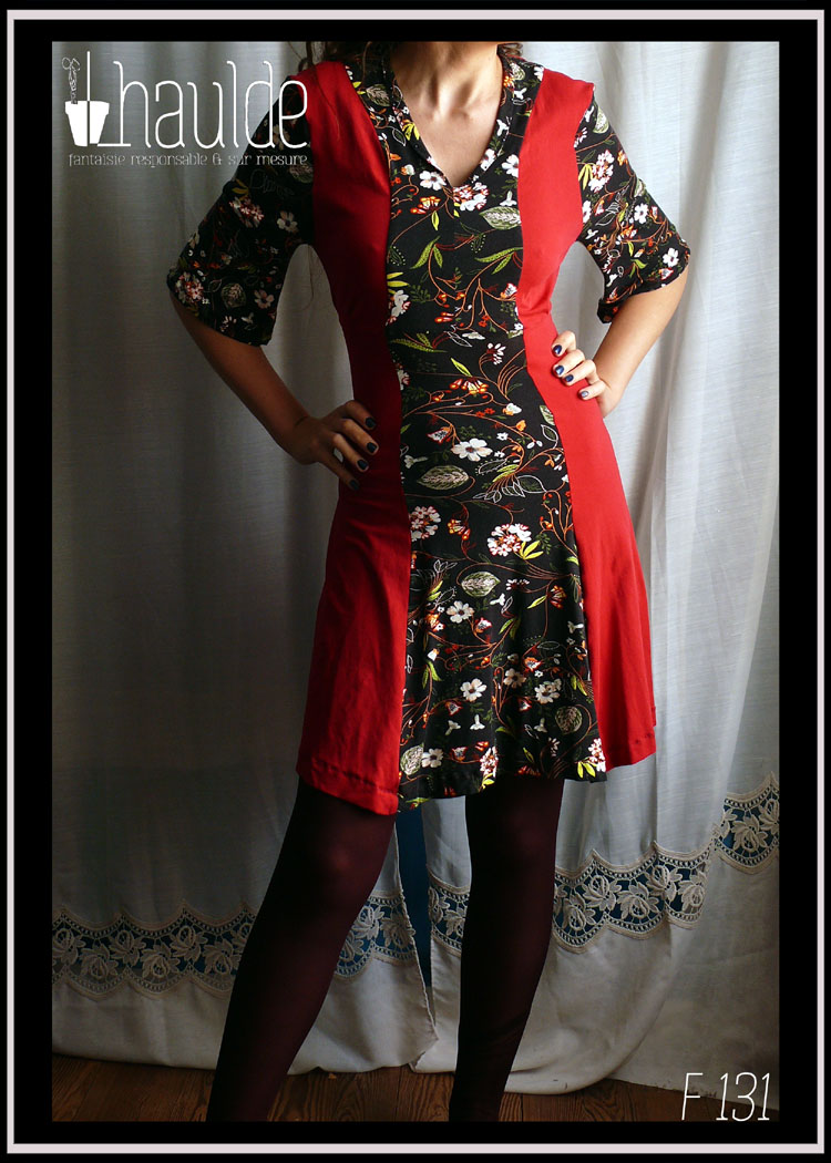 Robe mi-longue, manches mi-longues évasées en jersey, noir imprimé fleurs au centre sur toute la longueur devant et pour les manches. Jersey rouge cerise pour les côtés et le dos. vue de face en pied, portée