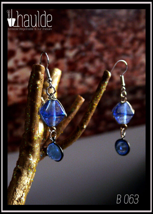 Paire de boucles d'oreilles montées sur crochet acier. Perles en verre bleu, reliées par de petits anneaux en acier. En haut polyèdre entouré de boucles d'acier, en-dessous demi-boule sertie