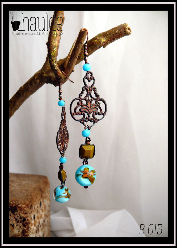 Boucles d'oreilles longues montées sur crochet d'acier, petite perle ronde couleur turquoise, estampe couleur bronze, petite perle ronde couleur turquoise, perle carrée vert-jaune enchassée dans de l'acier, perle bleue ronde à incrustation dorée