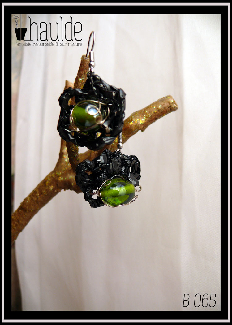 paire de boucles d'oreilles en VHS crochetée montée sur crochet d'acier. Vidéo crochetée de forme ovale avec en son centre une grosse perle en verre vert. Vue de la paire, de face