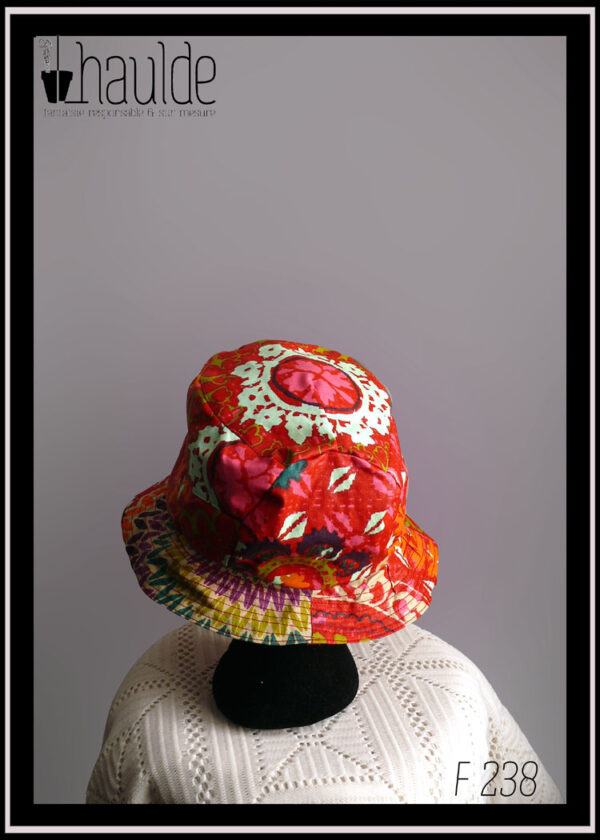 Mannequin tête vue de dos portant un bob rouge à motifs multicolore de type fleurs stylisées et points de tricot