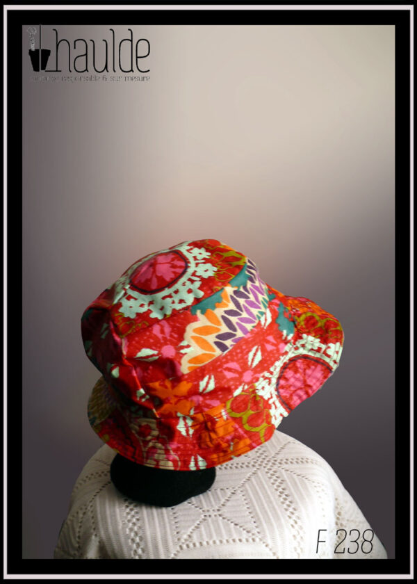 Mannequin tête vue de profil portant un bob rouge à motifs multicolore de type fleurs stylisées et points de tricot