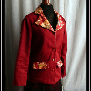 Veste en sergé rouge foncé, col et et rabats des poches en toile rouge imprimée de motifs fleuris et de grues, à l'esthétique japonaise. Vu de trois quarts sur un mannequin de couture