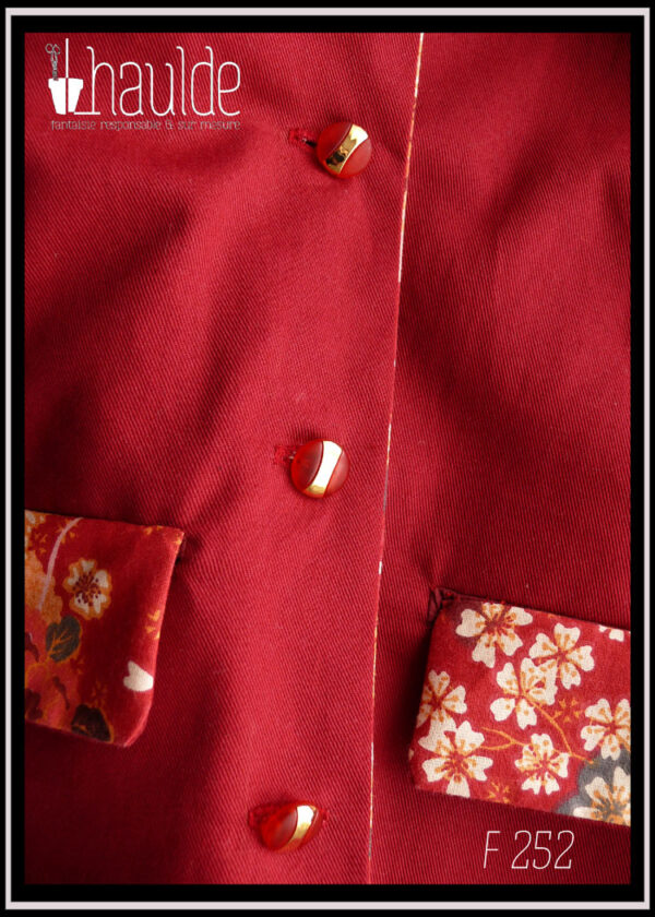Veste en sergé rouge foncé, col et et rabats des poches en toile rouge imprimée de motifs fleuris et de grues, à l'esthétique japonaise. Détails des boutons et des rabats de poches