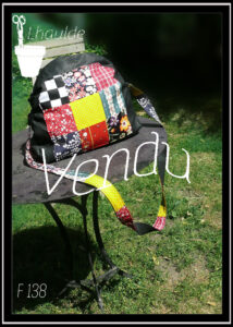 sac en simili cuir arrondi sur le dessus et garni de carrés de tissus variés, mention vendu