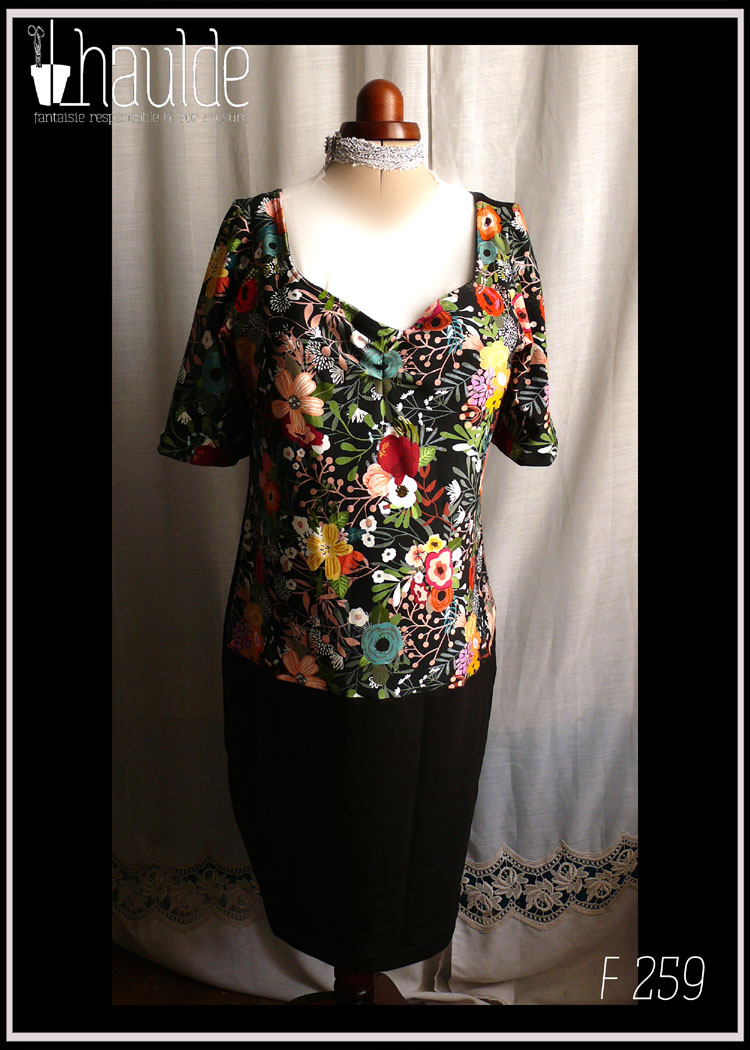 Robe mi-longue à manches courtes légèrement bouffante, décolleté en forme de coeur. Haut devant et manches noir imprimé grosses fleurs, jupe et dos noir Vue de face sur un mannequin de couture
