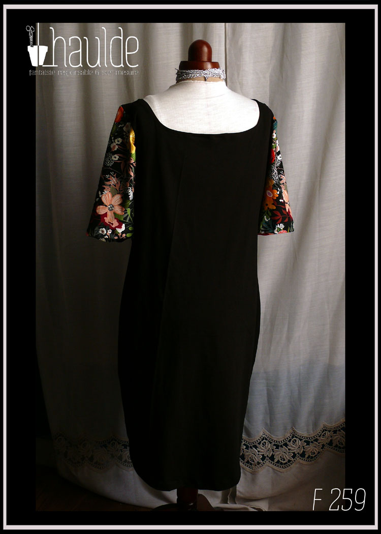 Robe mi-longue à manches courtes légèrement bouffante, décolleté en forme de coeur. Haut devant et manches noir imprimé grosses fleurs, jupe et dos noir Vue de dos sur un mannequin de couture