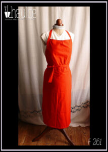 Tablier de potier (deux pans fendus pour les jambes) en toile légère rouge, ceinture longue pouvant se nouer à l'avant. Vu de face sur un mannequin de couture